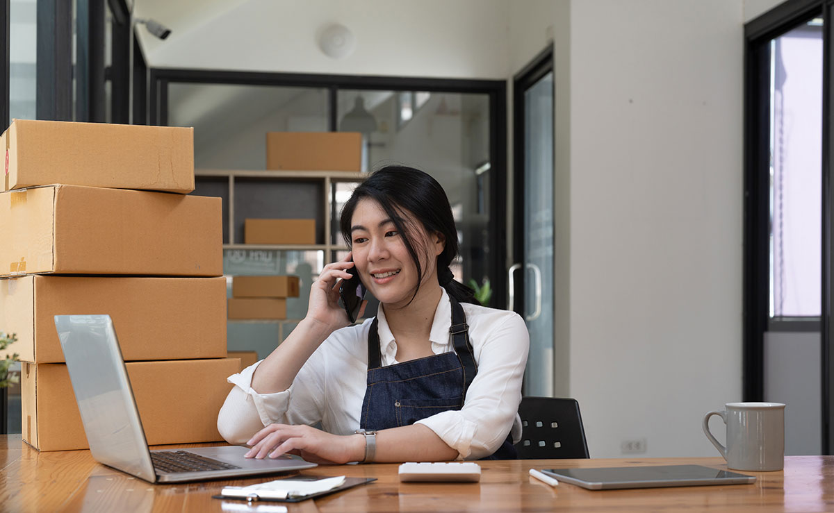 young business owner on the phone surrounded by boxes