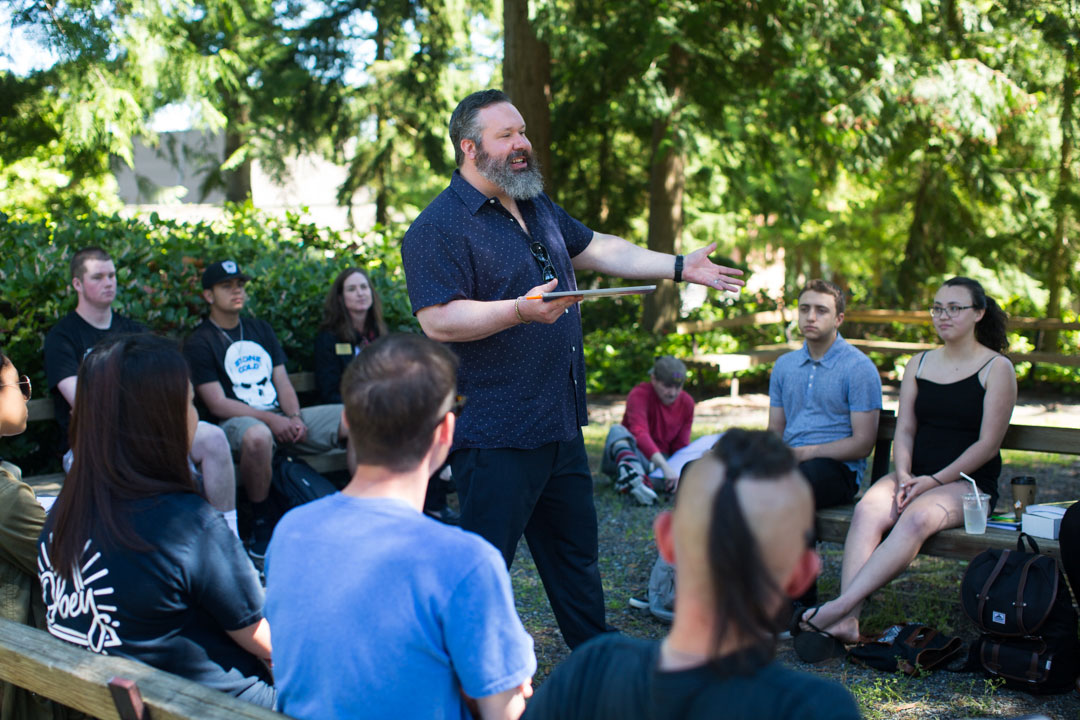 students sitting outside listening to instructor