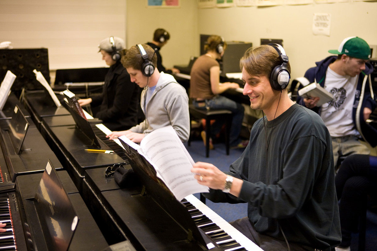 students sitting at pianos wearing headphones while practicing